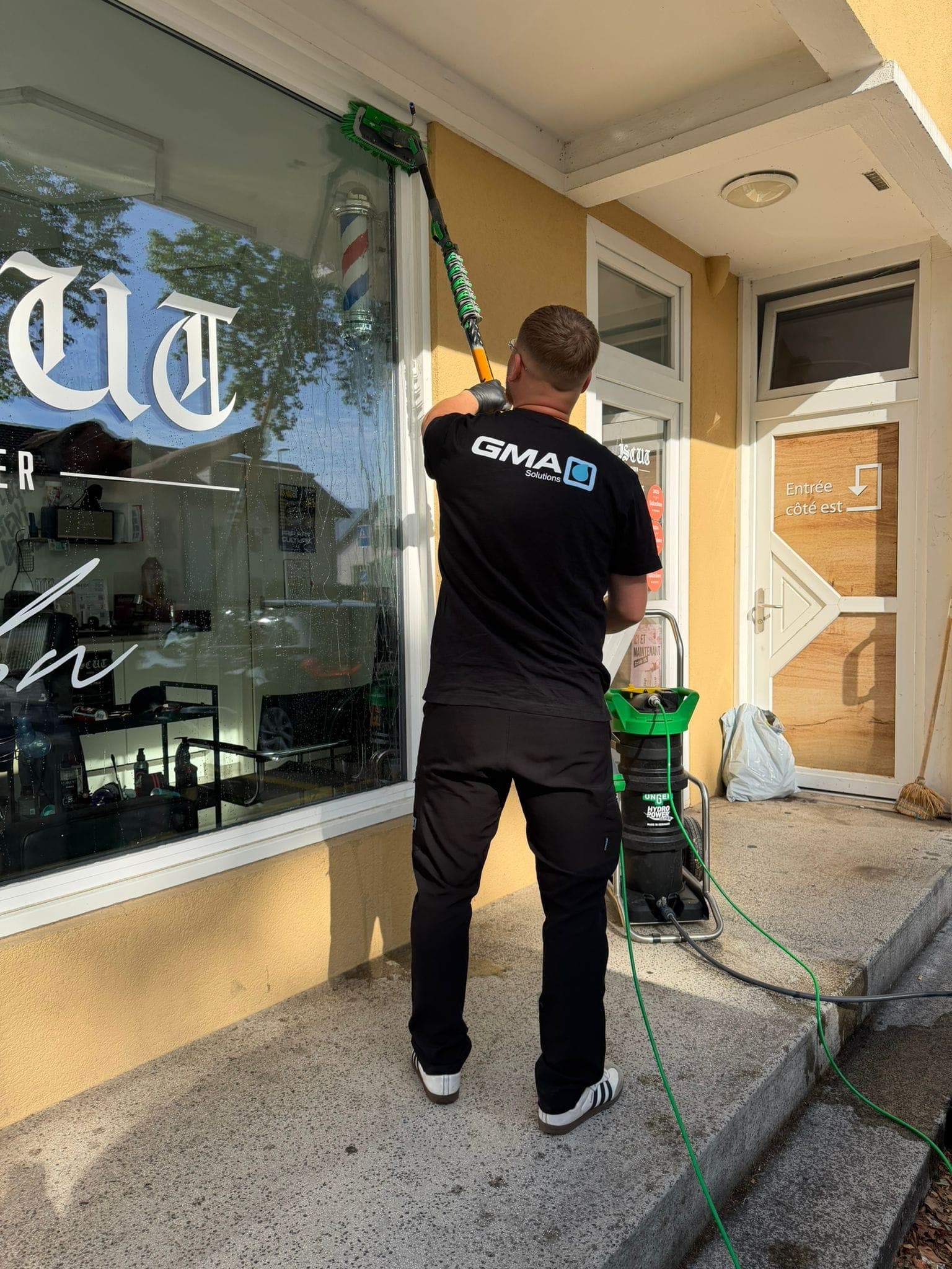 Agent GMA Solutions nettoyant une vitrine à Yverdon-les-Bains